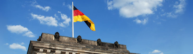 Deutsche Flagge vor blauem Himmel über dem Reichstagsgebäude in Berlin